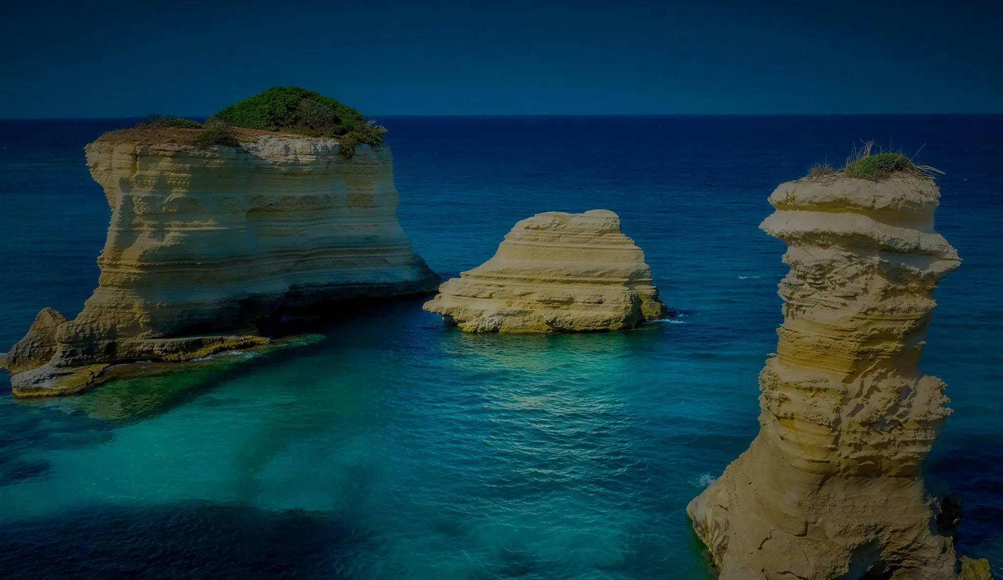 Faraglione di roccia calcarea nel mare turchese lungo la costa del Salento